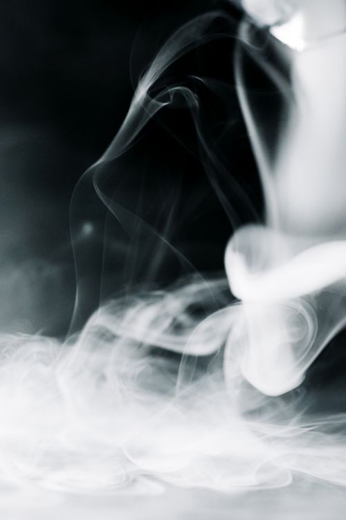 Free Captivating close-up of swirling smoke on a dark background. Ideal for creative projects. Stock Photo