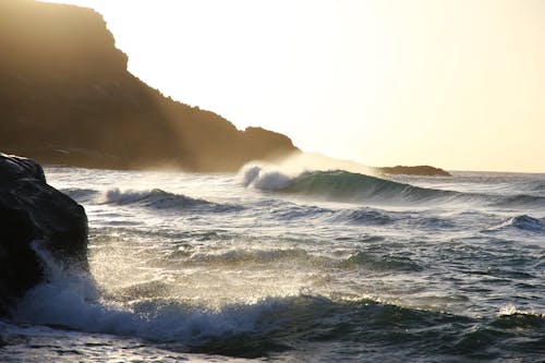 Tidal Waves Beside Mountain Slop during Daytime