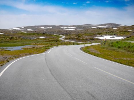 A captivating view of a winding road through hills with patches of snow, perfect for travel themes.