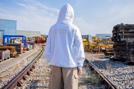 Man in White Hoodie Standing on Train Rail