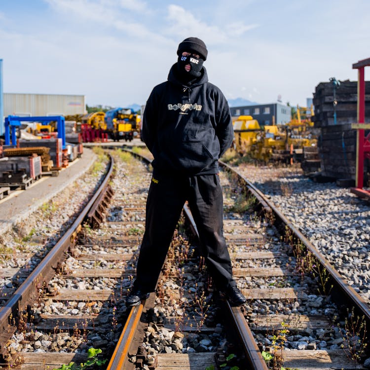 Man In Black Jacket Standing On Train Tracks