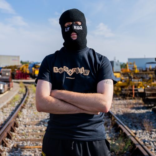 Free A person wearing a mask stands on train tracks, capturing a streetwear fashion aesthetic. Stock Photo