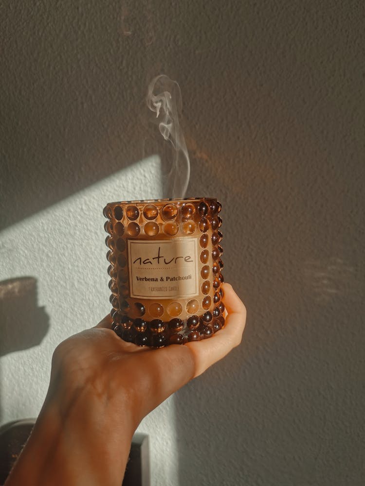 A Person Holding A Glass Jar With Scented Candle