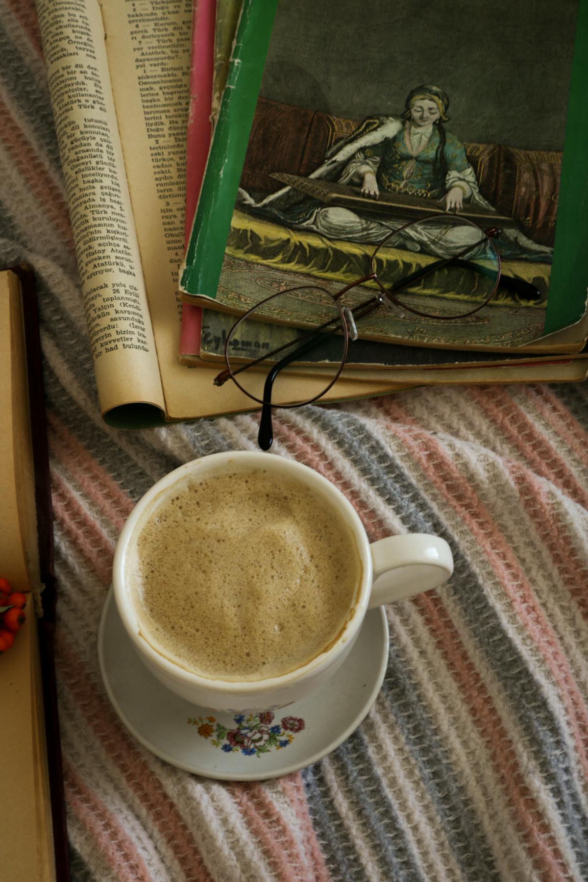 A wooden tray with two mugs of frothy lattes and a small bowl of cocoa powder on a rustic table