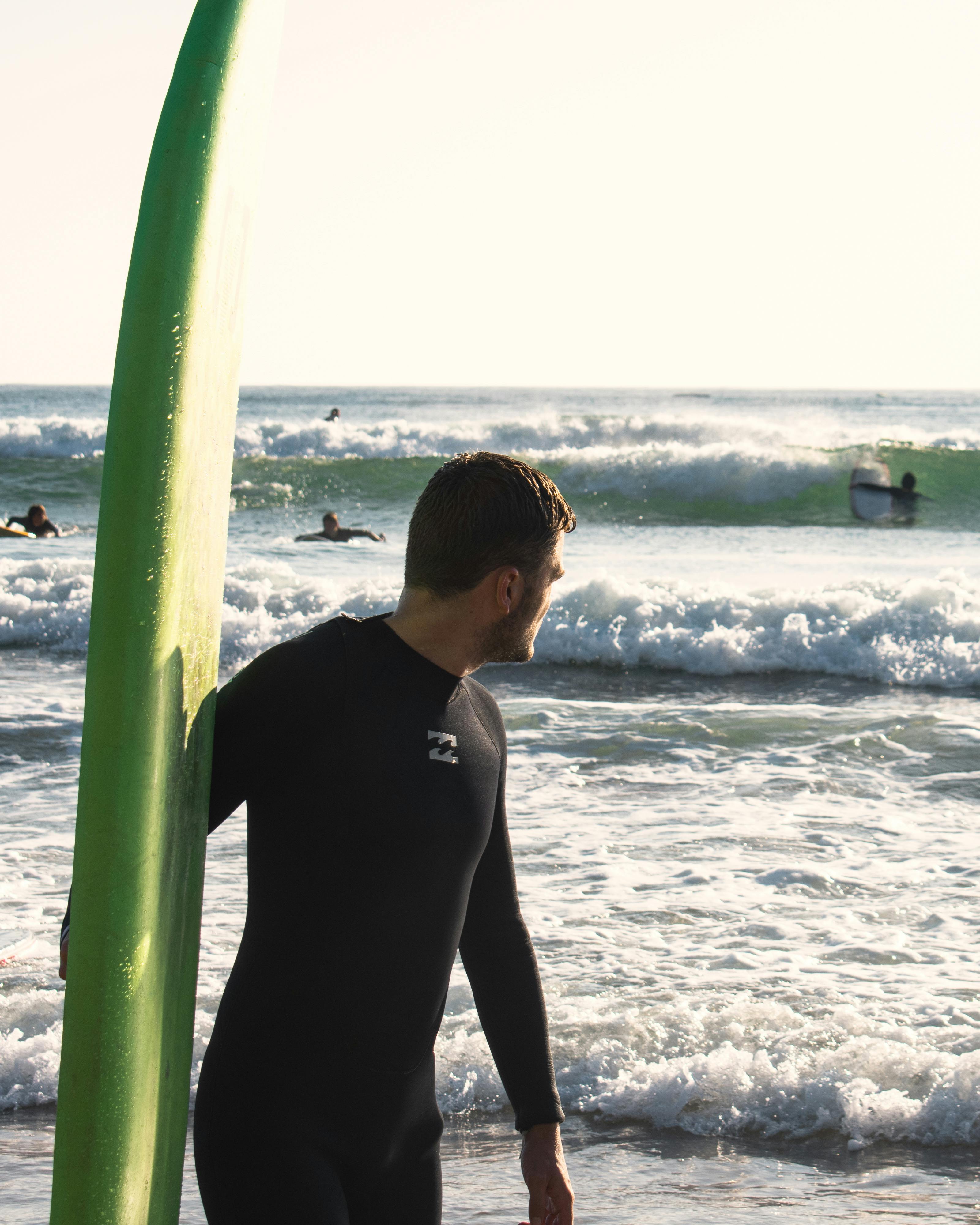 Smiling Man Holding a Surfboard Up · Free Stock Photo