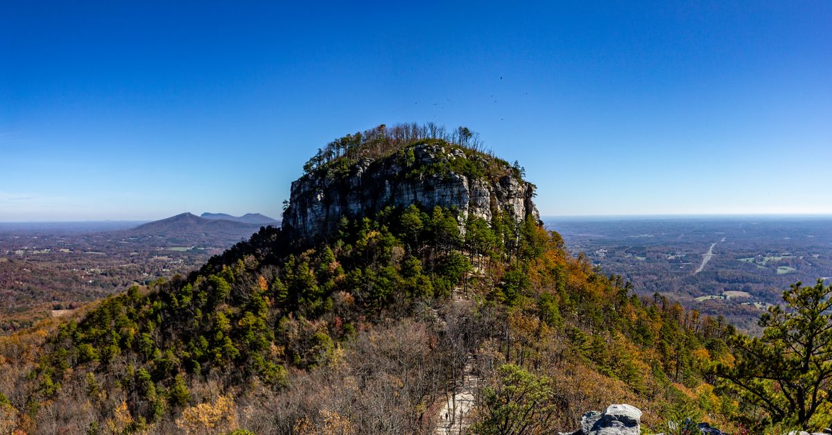 A stunning aerial view of Pilot Mountain in Pinnacle, North Carolina with clear blue skies and autumn foliage.