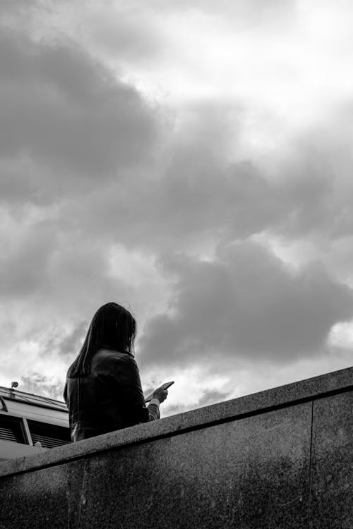 Grayscale Photo of Woman Leaning on Concrete Wall
