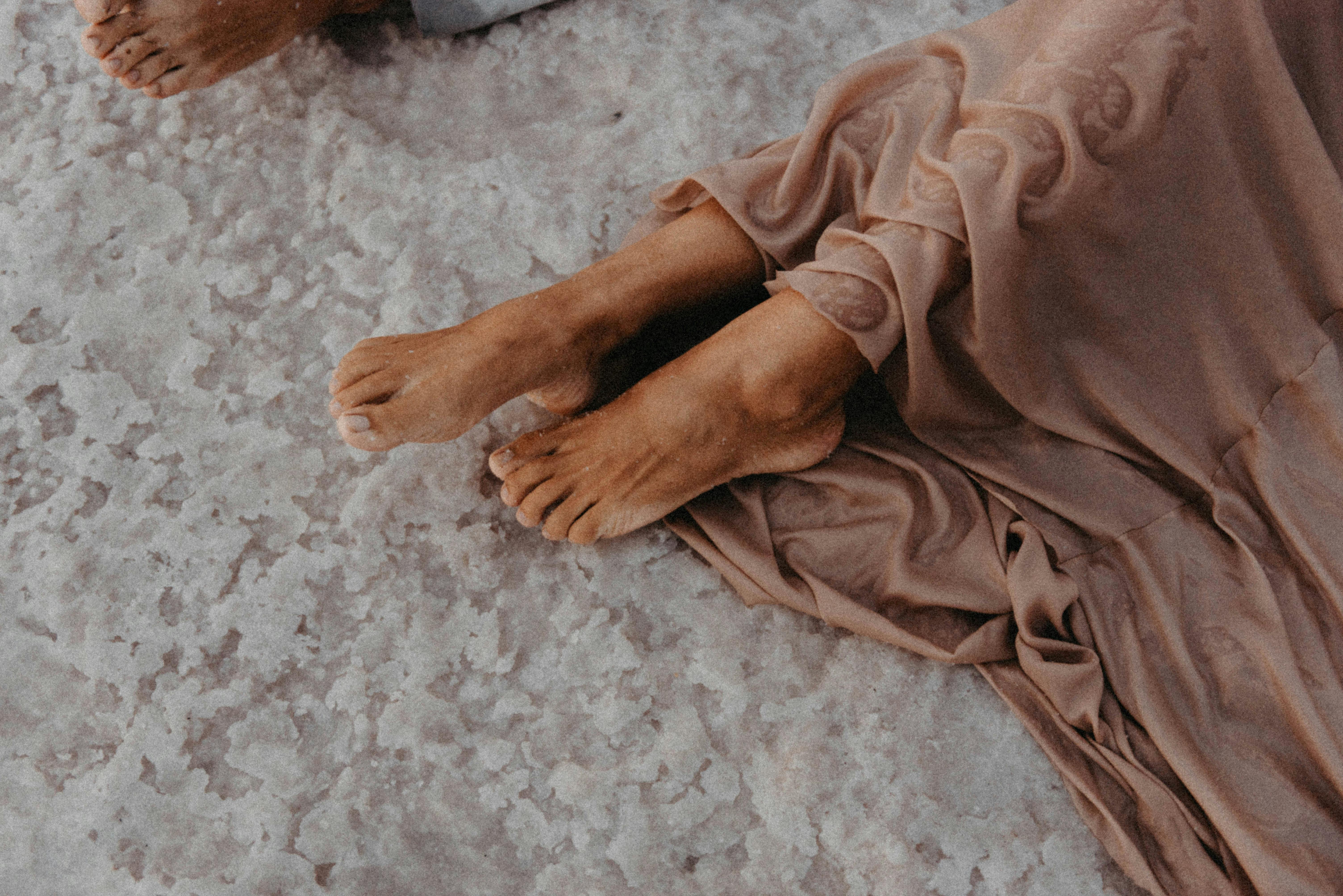 barefoot person lying on rocks