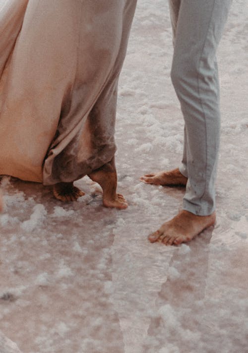 Woman and Man Standing Barefoot in Water