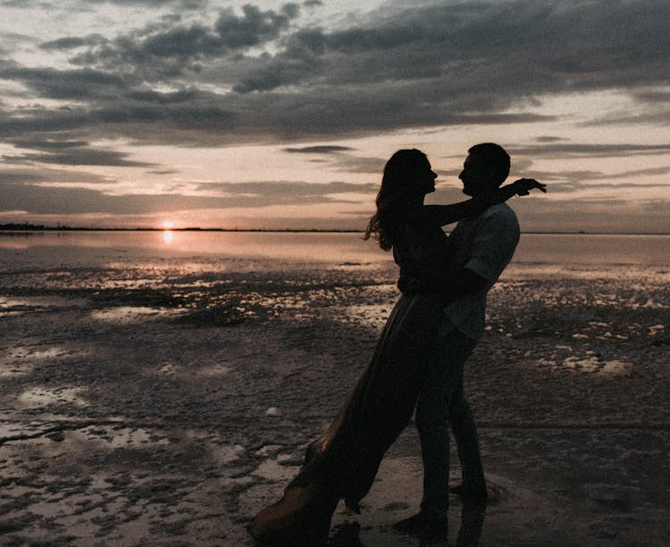 Silhouette Of Couple Dancing On Sea Shore