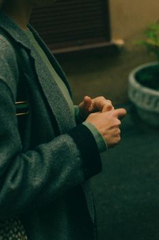 A person in a gray jacket stands outdoors in a contemplative pose.