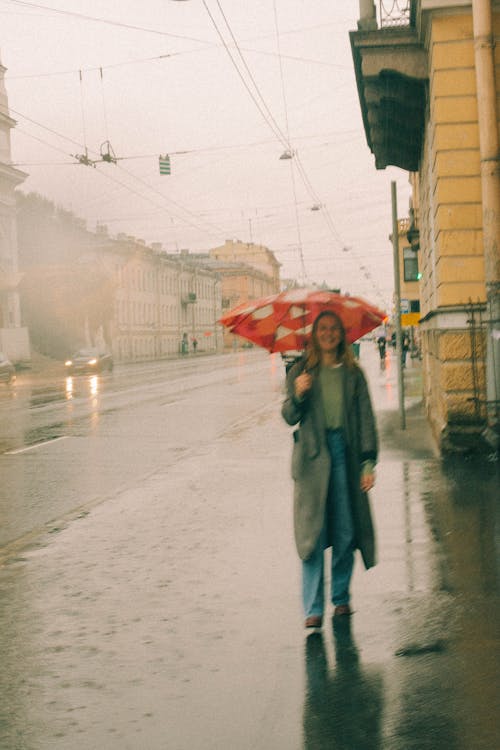 A Woman Walking in the Rain while Holding an Umbrella