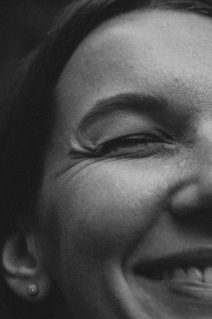 Close-up of a woman's smiling face in black and white photography.