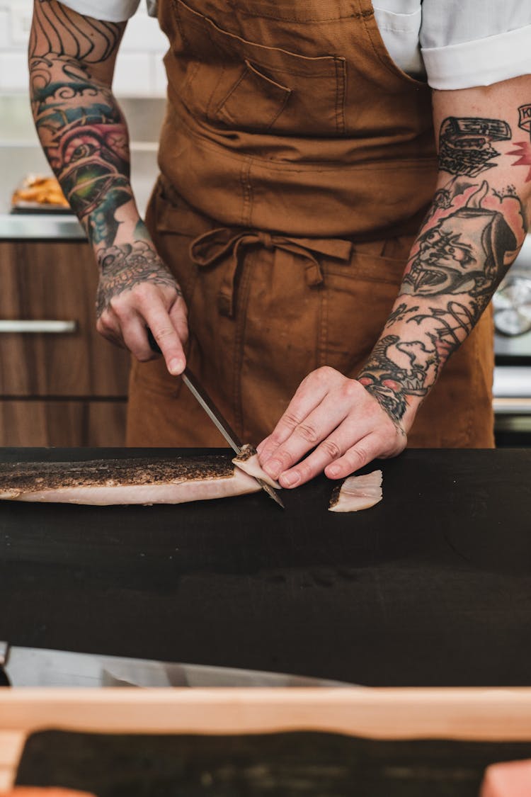 A Man Slicing A Fish While Making A Sushi