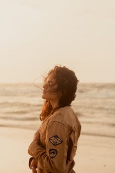 Caucasian woman in brown jacket enjoying a tranquil sunset on a Brazilian beach.