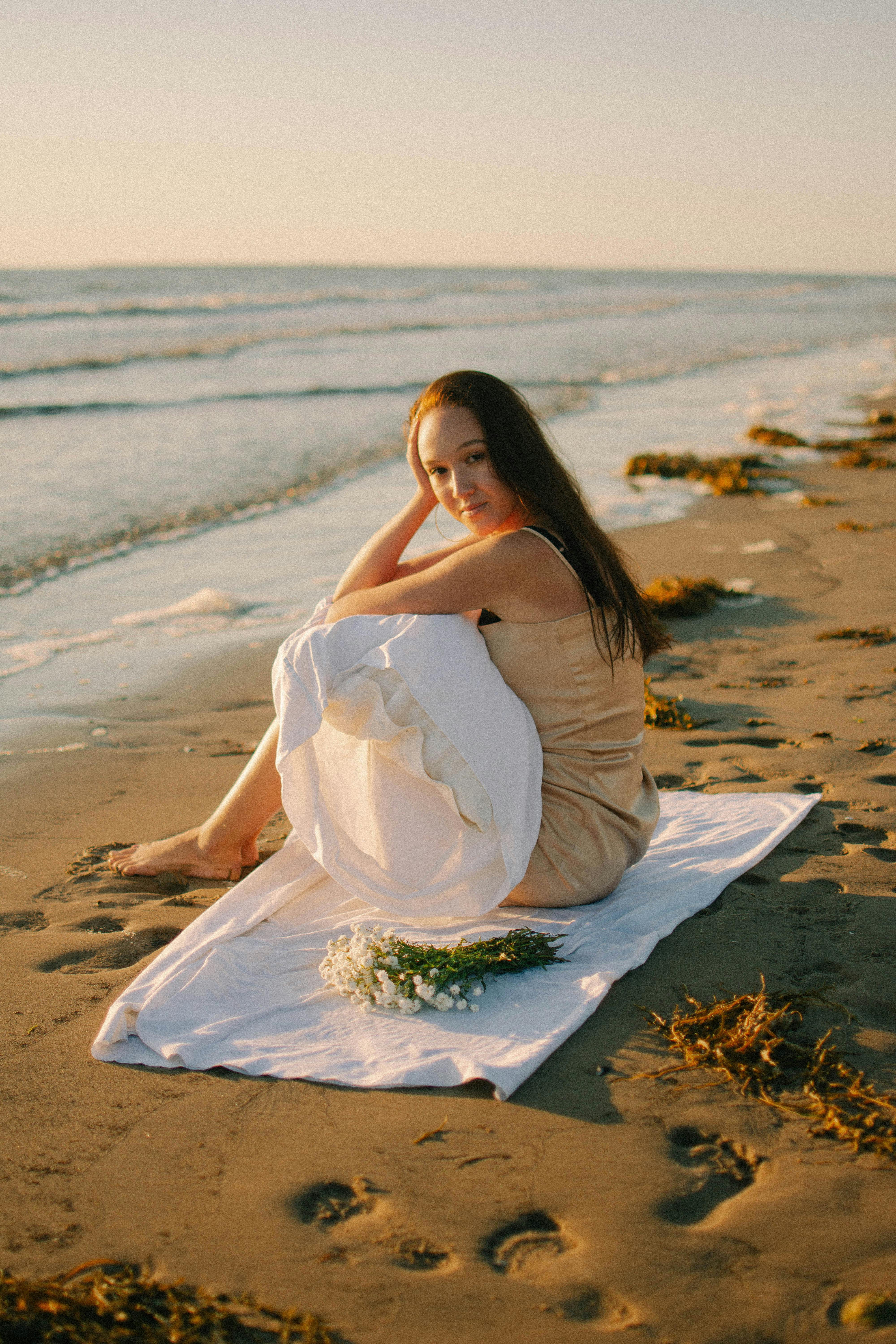 一个女人坐在海滩上在日落，享受宁静的海浪宁静的肖像