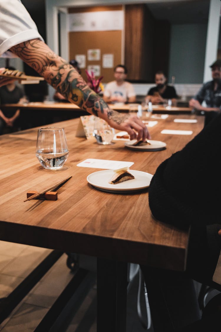 Person With Arm Tattoo Setting The Table