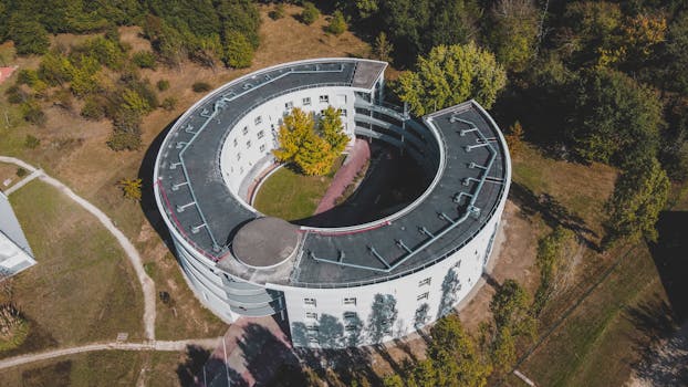 Drone shot of a unique round building surrounded by greenery in Bordeaux, France.