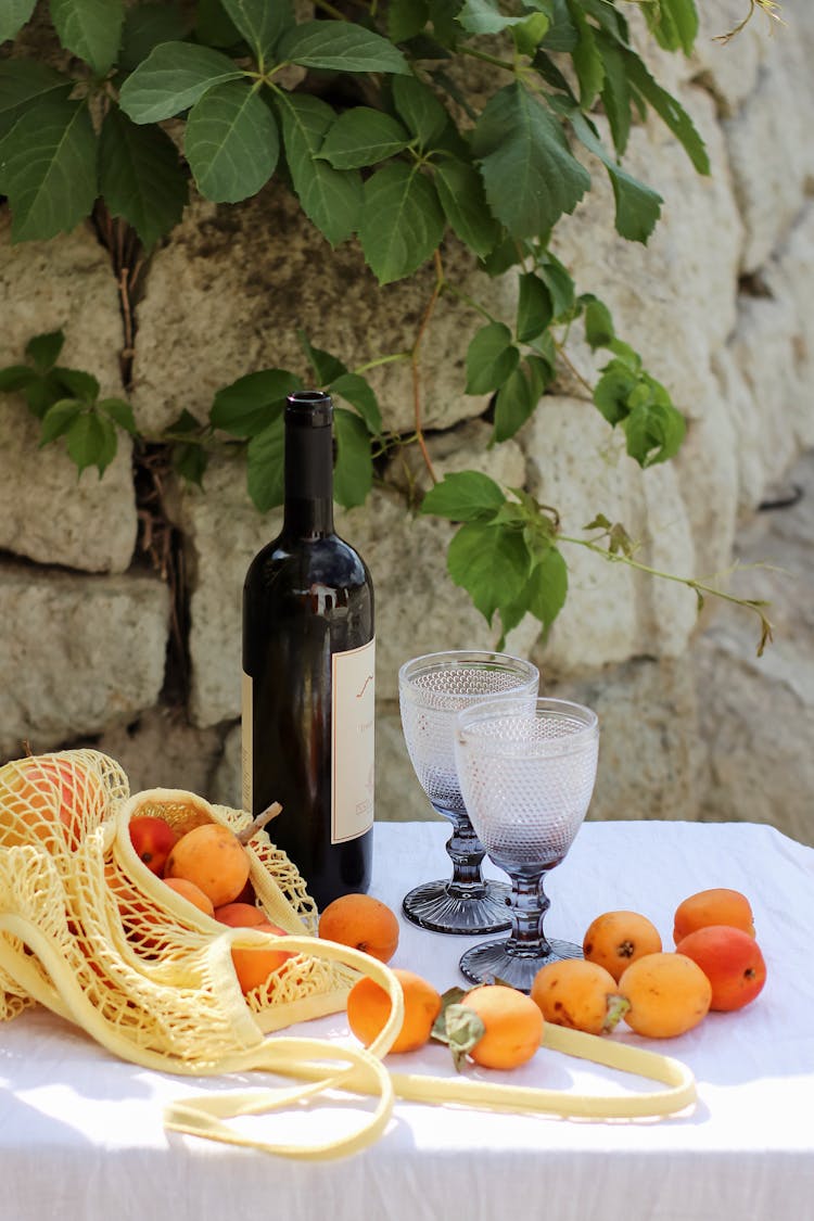 Outdoor Photo Of Table With Oranges, Wine And Wine Glasses