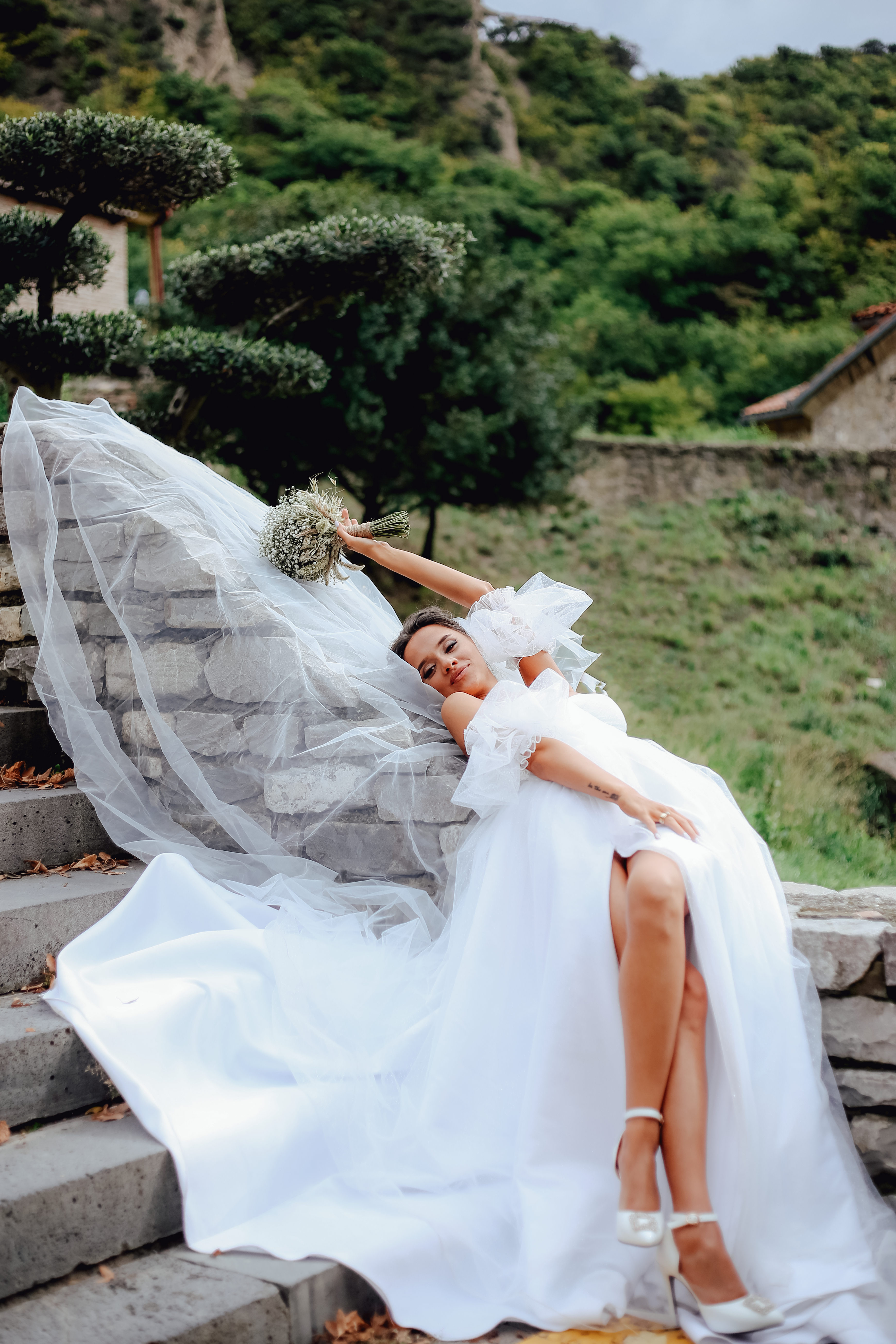 A Woman in White Wedding Dress Lying on the Stairs while Holding a ...