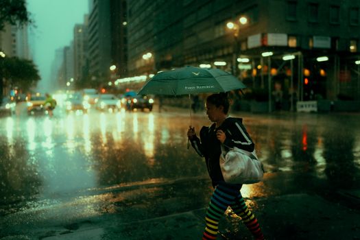 Woman walking with umbrella on a rainy New York street, reflecting urban life.
