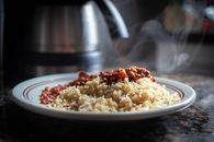 Close-up of steaming rice with chili beans on a plate, showcasing savory food.