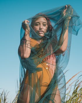 Woman standing outdoors in New Smyrna Beach with a blue veil against a clear sky.