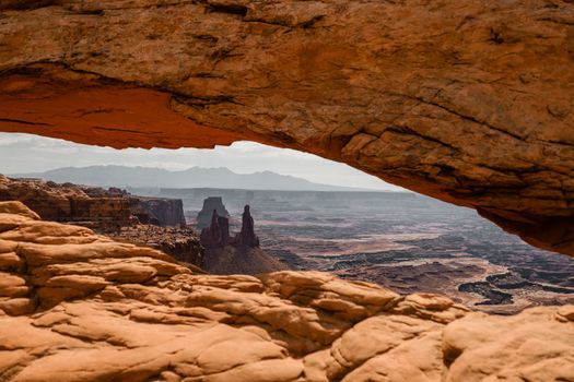 Breathtaking view through Mesa Arch in Utah's Canyonlands National Park at sunset. Marvel at the stunning rock formations.