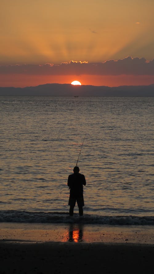 Silhouette of a Man Fishing during Sunset