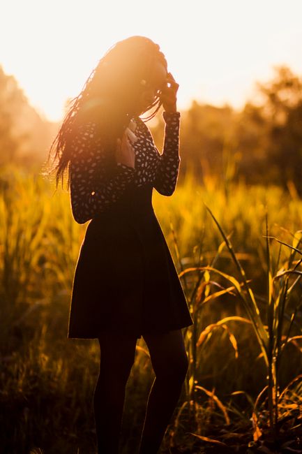 A woman enjoys a serene sunset in a grassy field, Kiambu, Kenya.