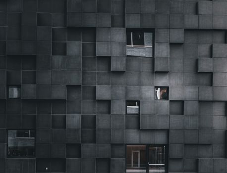 Modern architectural facade with geometric patterns and scattered windows.