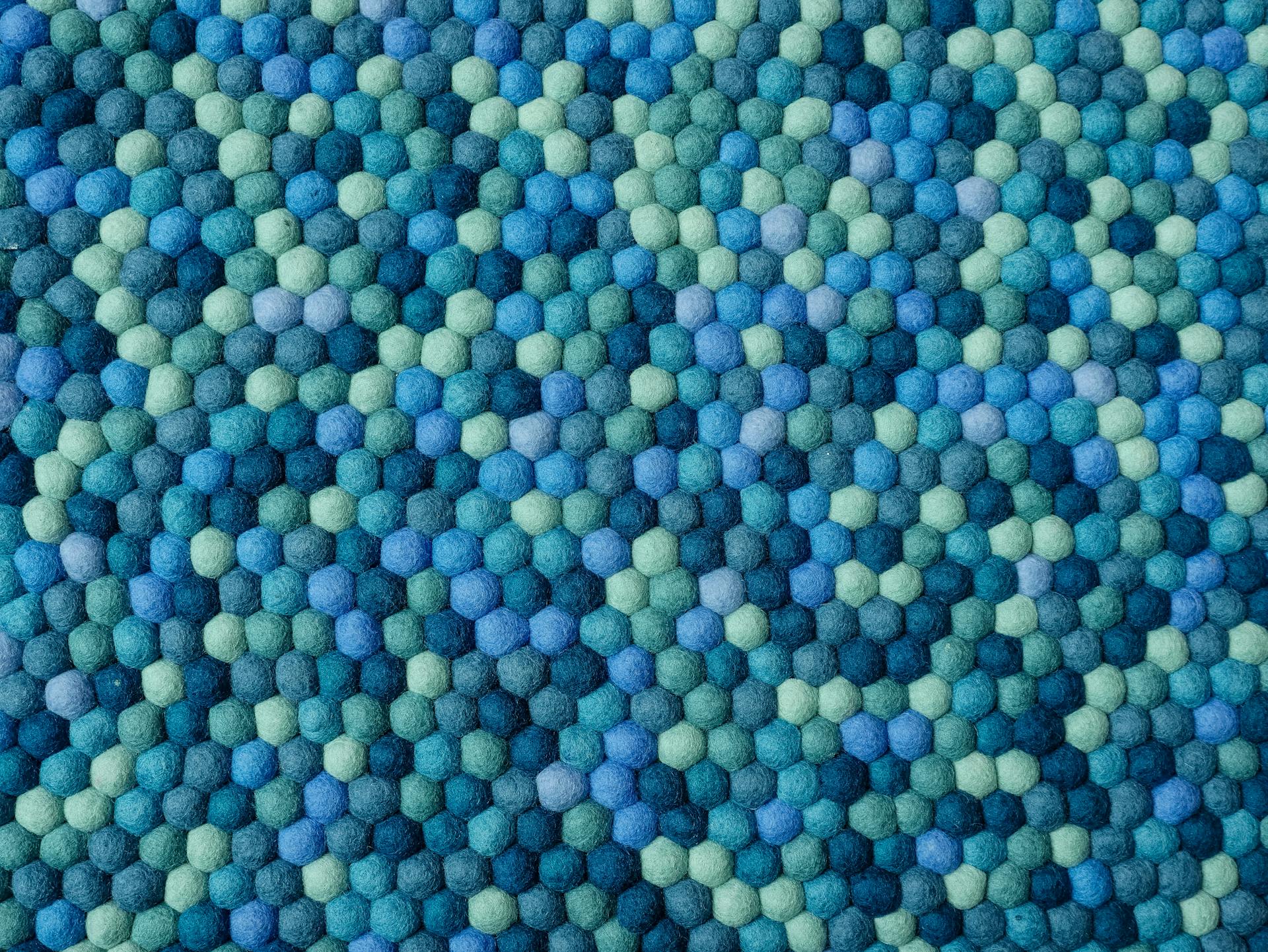 Closeup of a vibrant blue and green felt textile with a geometric hexagonal pattern.