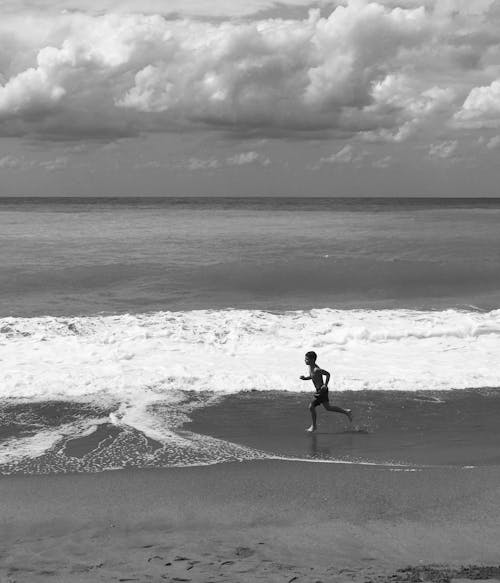 Free A Boy Running on Beach Shore Stock Photo