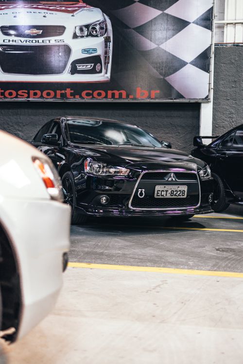 Free Sleek black Mitsubishi parked indoors with a racing-themed backdrop. Stock Photo