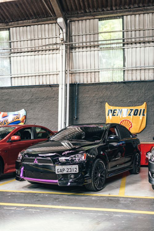 Free Shiny black Mitsubishi car parked in an indoor garage with visible emblem and license plate. Stock Photo