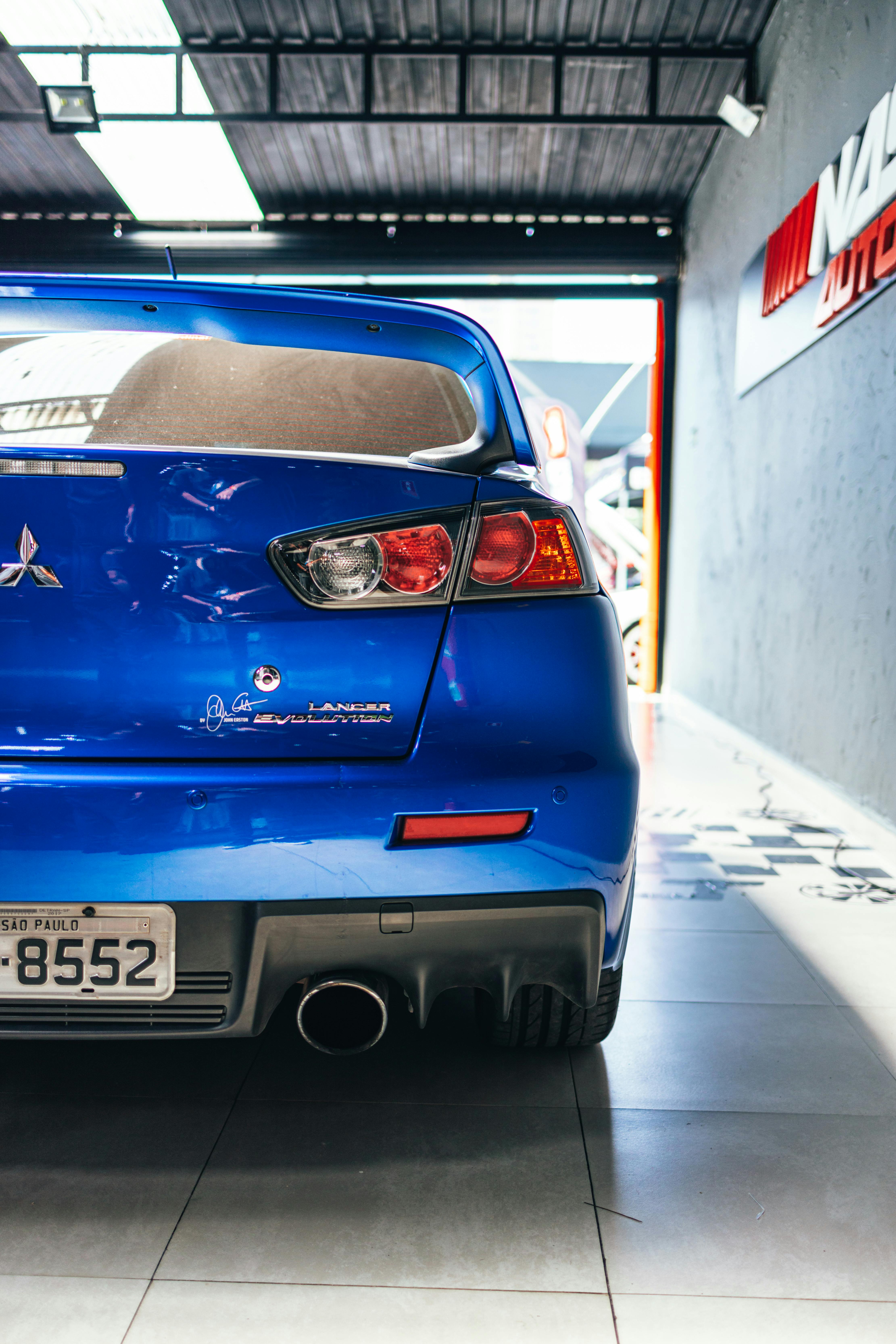 Rear view of a blue Mitsubishi Lancer Evolution parked in an indoor garage.
