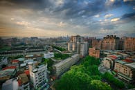 在引人注目的云层下，城市景观捕捉到充满活力的天际线，前景是郁郁葱葱的绿色植物