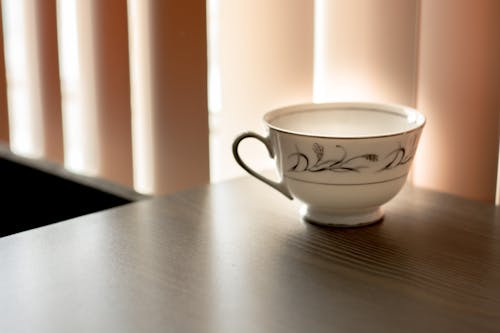 White and Black Ceramic Teacup on Brown Wooden Surface