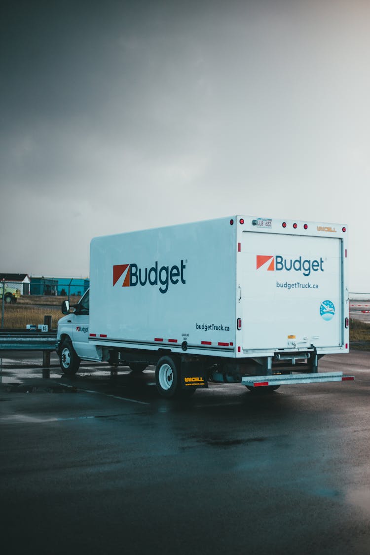 White And Red Box Truck Parked On Wet Ground 