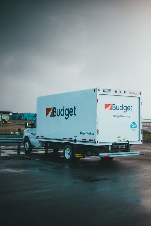 Free A Budget rental truck parked on a wet asphalt in an outdoor lot under a cloudy sky. Stock Photo