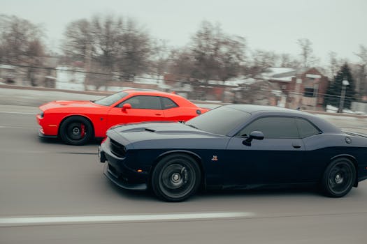 Dynamic race between two muscle cars on a city street showcasing speed and blurred motion.
