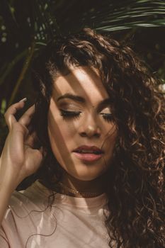 Close-up of a woman with curly hair in soft lighting, creating a serene and artistic mood.