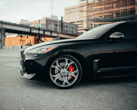 A sleek black Kia Stinger GT2 parked in a downtown Des Moines urban landscape.