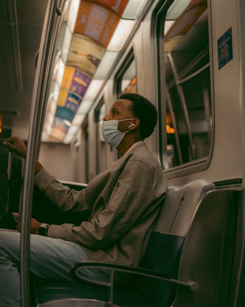 Photo of a Man with a Facemask Sitting Inside a Train