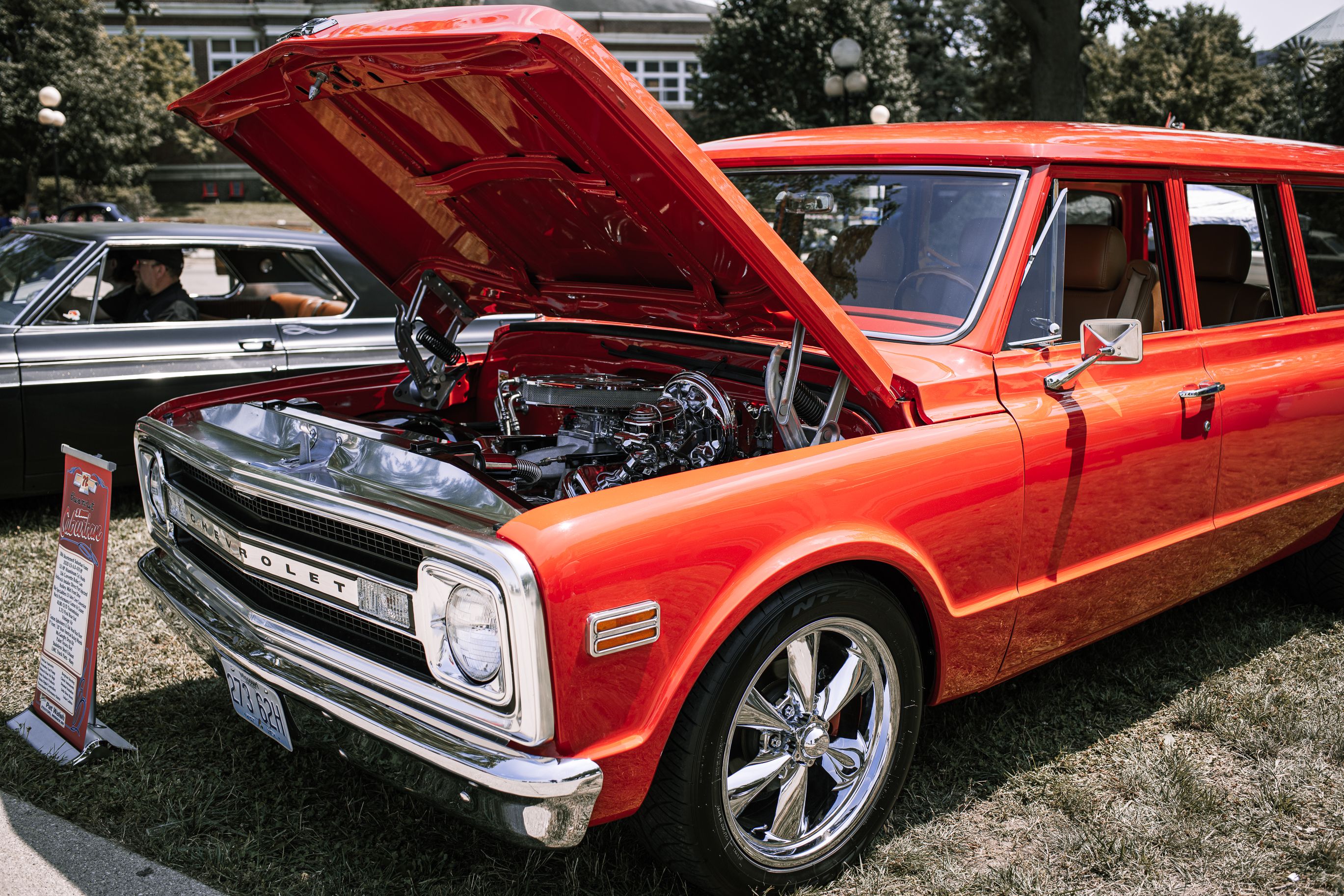 Vintage red Chevrolet car with hood open, showcasing engine at Des Moines car show.