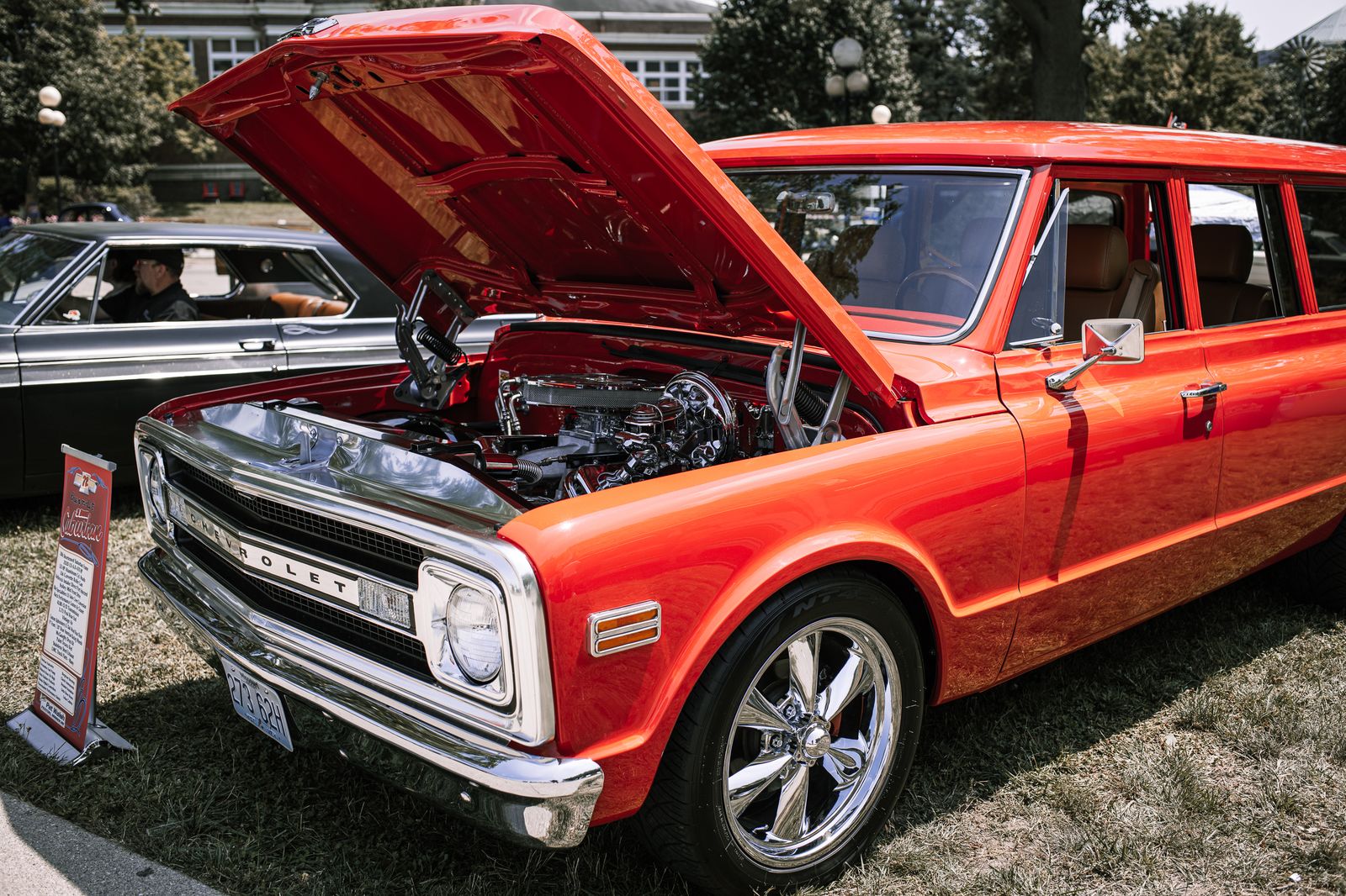 Vintage red Chevrolet car with hood open, showcasing engine at Des Moines car show.
