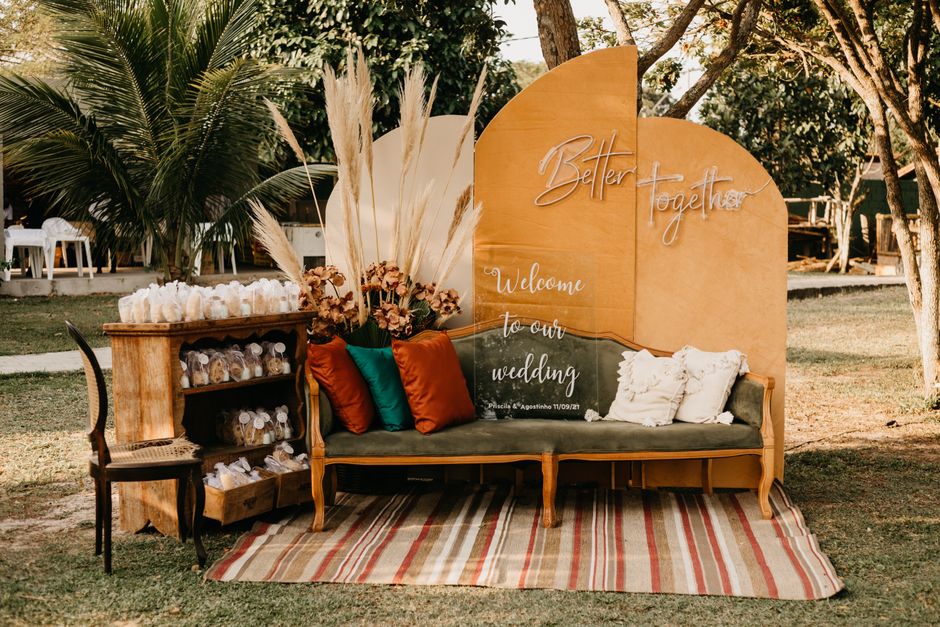 Elegant wedding reception decor with sofa, pillows, and welcoming signs outdoors.