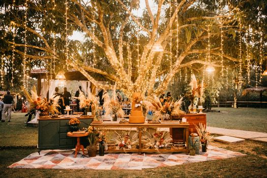 Beautifully decorated outdoor wedding with cake, flowers, and string lights at twilight.