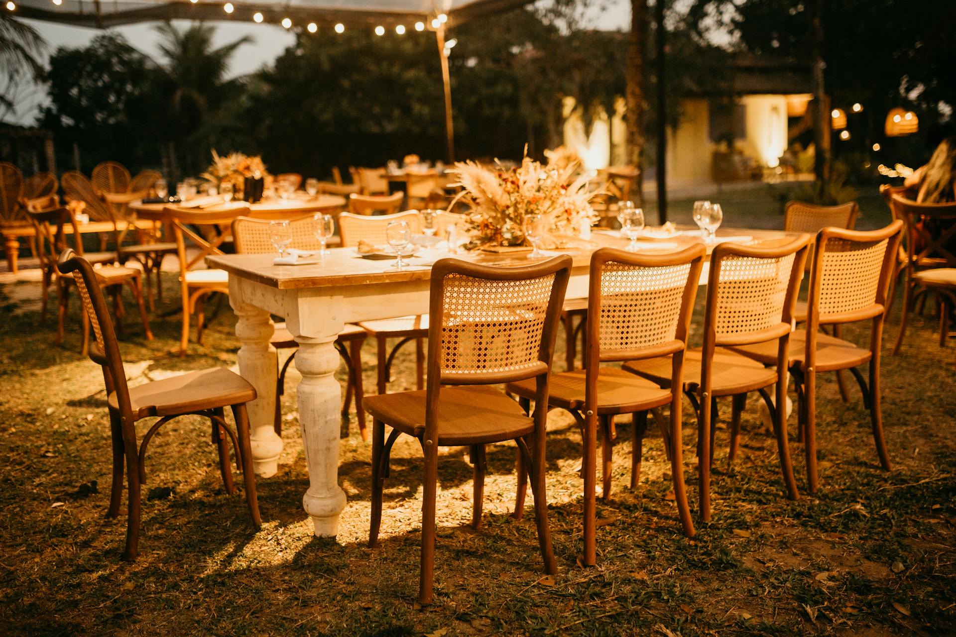 Beautifully arranged outdoor wedding reception tables under warm evening lights.