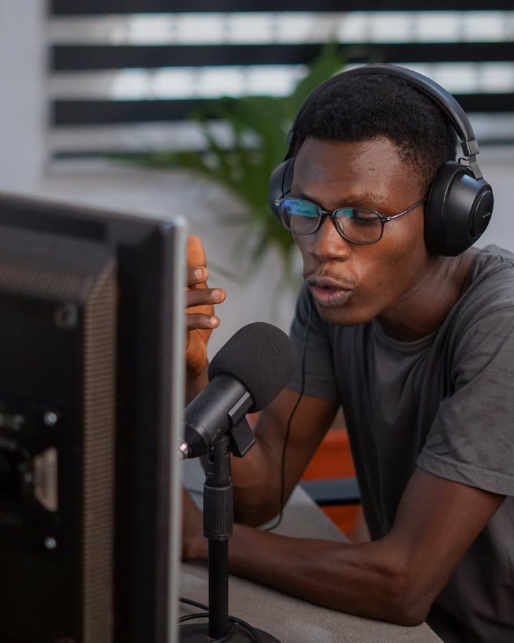 A Man Sitting At The Desk With Headphones And Microphone